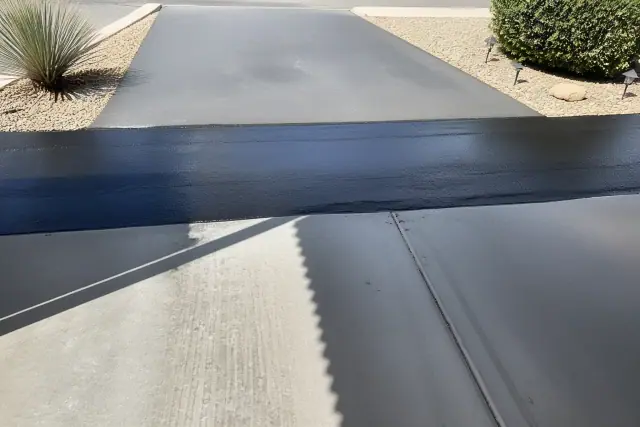 Fresh asphalt seal coating on a residential driveway transition in Phoenix, AZ.