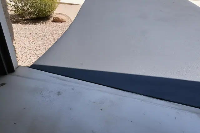 Fresh asphalt sealcoating at the transition between a residential garage and driveway in Tempe, AZ.