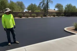 Worker in a high-visibility vest standing by a smooth, black sealcoated parking lot in Tempe, AZ.