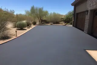 Dark, smooth asphalt sealcoating on a residential driveway with desert shrubs in Tempe, AZ.