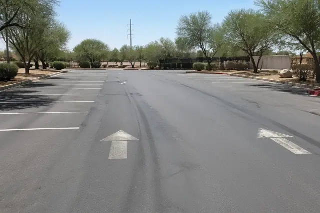 Asphalt parking lot with heat shimmer and tire ruts under harsh summer sun in Tempe, AZ.