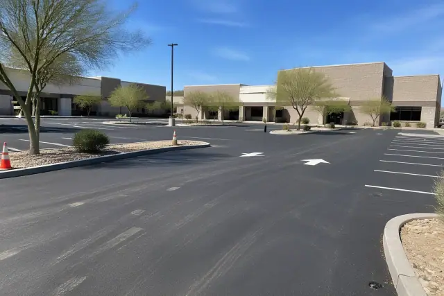 Newly paved asphalt parking lot with line striping and chip seal in front of retail stores in Tempe, AZ.