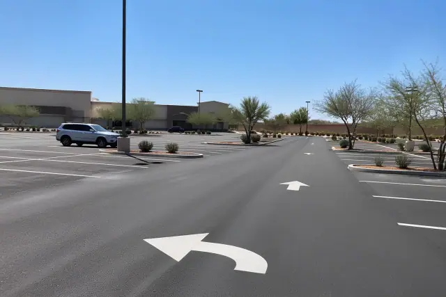 Newly paved commercial parking lot with painted stall markers and directional arrows in Tempe, AZ.