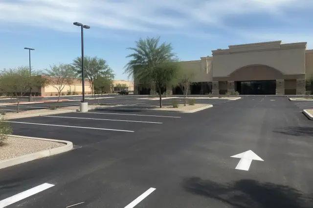 Newly paved asphalt parking lot with fresh stall striping and directional arrows at a retail center in Peoria, AZ.