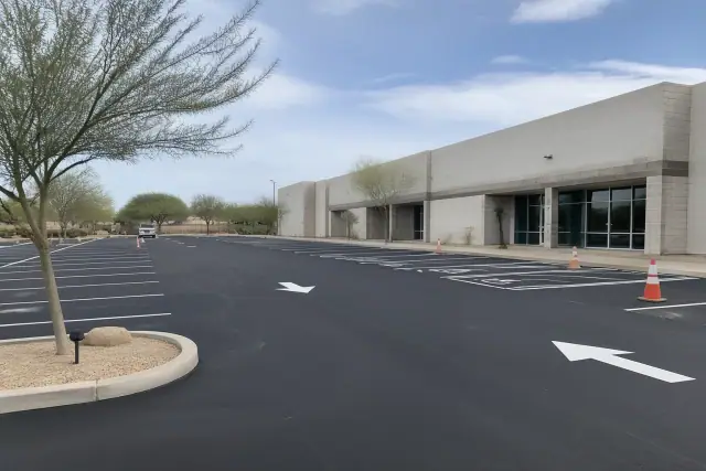 Freshly paved parking lot with new white stall markings and directional arrows at a retail center in Glendale, AZ.