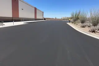 Technician inspecting a freshly paved asphalt loading zone with ocotillo and prickly pear in Tempe, AZ.