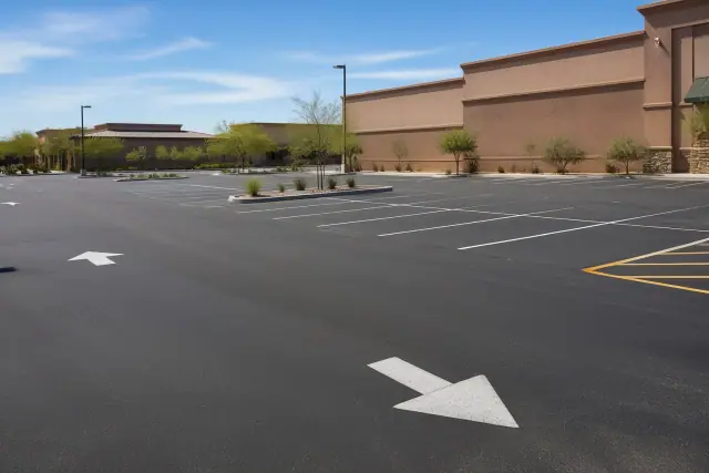 Newly paved retail parking lot with painted stall markers and directional arrows in Tempe, AZ.