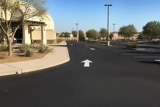 Freshly sealcoated parking lot with painted stall markers and xeriscaping in Tempe, AZ.