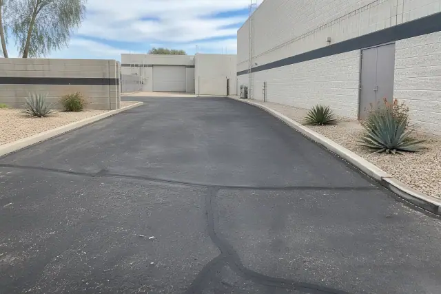Newly paved asphalt with crack repairs at a commercial building rear entrance in Tempe, AZ.