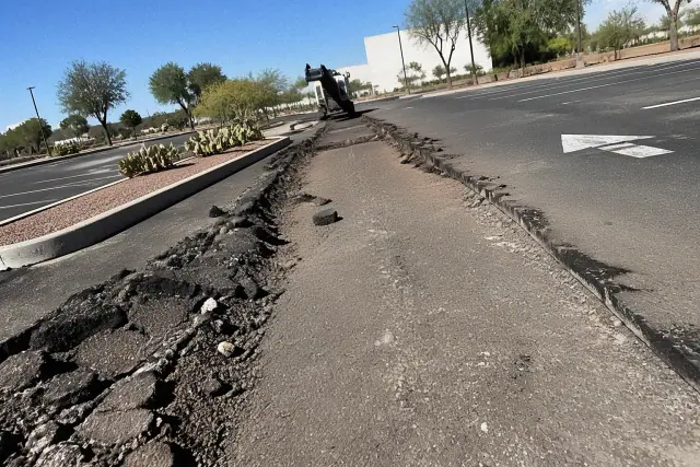 Asphalt milling and removal process showing jagged pavement and sub-base in a Tempe, AZ parking lot.
