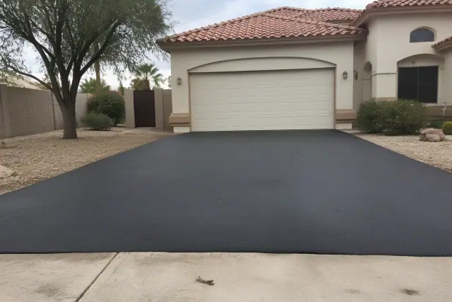 Newly paved asphalt driveway at a house in Glendale, AZ, showing the transition from the garage to the street.
