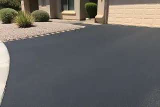 Freshly paved asphalt driveway with gravel landscaping and stucco walls in Tempe, AZ.