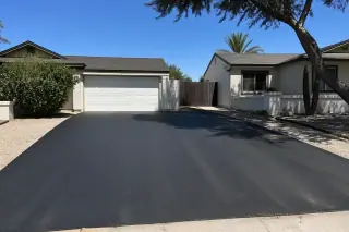 Smooth, newly rolled asphalt driveway in front of a xeriscaped home under the bright sun in Tempe, AZ.