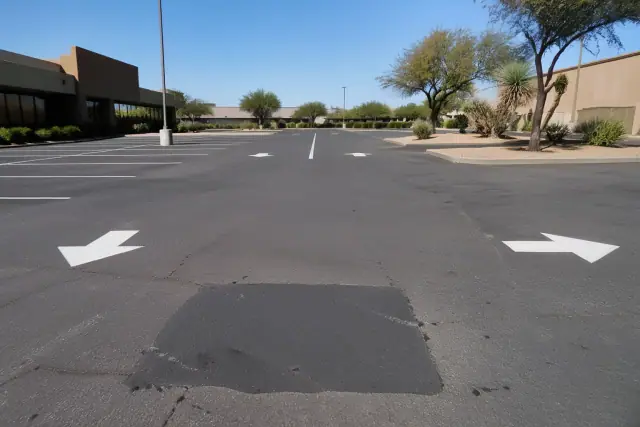 Newly paved parking lot with fresh asphalt repairs and painted stall markers at a retail center in Tempe, AZ.