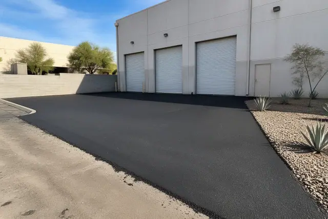 Newly paved asphalt apron in front of a commercial warehouse in Tempe, AZ, featuring desert landscaping.