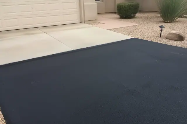 New asphalt driveway transition to a residential garage in Tempe, AZ, with desert landscaping.
