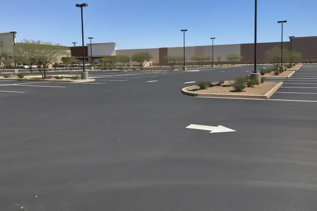 Newly paved asphalt parking lot with painted stall markers and directional arrows in Queen Creek, AZ.