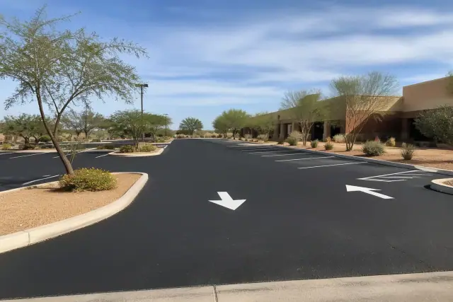 Newly paved parking lot at a retail center in Tempe, AZ with fresh asphalt, painted stall markers, and desert shrubs.