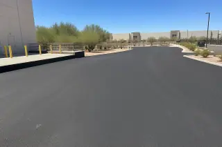 Smooth, freshly paved asphalt loading zone with gravel xeriscaping under a clear blue sky in Tempe, AZ.