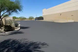 Freshly paved asphalt loading zone with agave and prickly pear plants at a commercial site in Tempe, AZ.