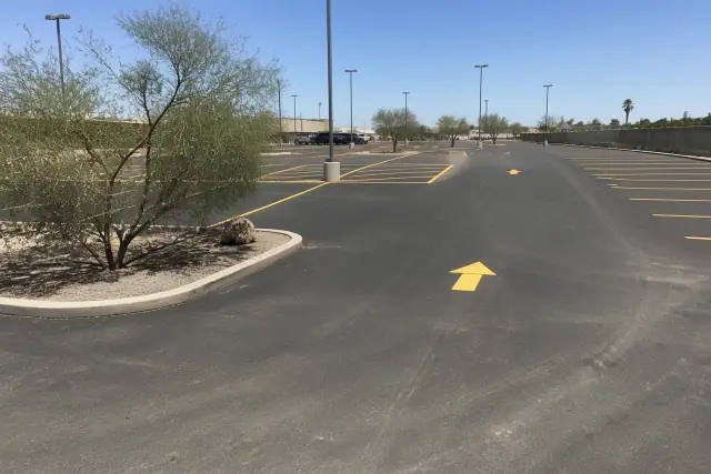 Asphalt parking lot repair with fresh painted lines and directional arrows in Tempe, AZ.