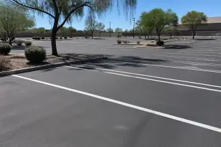 Freshly painted parking stall lines on smooth asphalt next to desert gravel landscaping in Tempe, AZ.