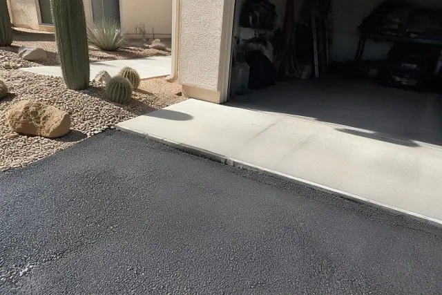 Newly installed asphalt driveway meeting a residential garage in Tempe, AZ.