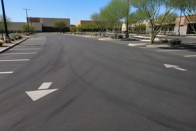 Tire scuffs and ruts in the heat-softened asphalt of a retail parking lot in Tempe, AZ.