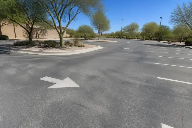Oxidized and sun-faded asphalt parking lot with directional arrows in Tempe, AZ.