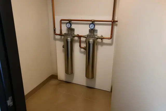 Commercial carbon filtration system with stainless steel housings and copper pipes in a Tempe, AZ office utility closet.