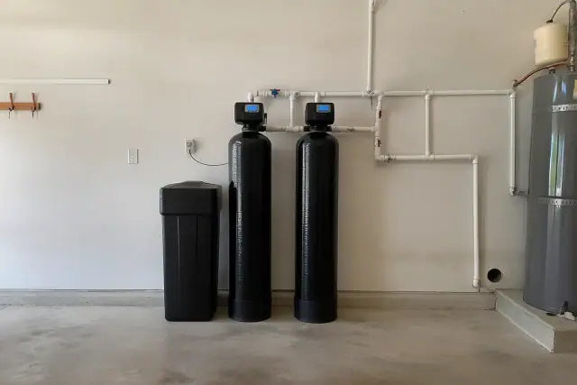 Commercial water softener system with two resin tanks and plumbing installed in a garage in Tempe, AZ.