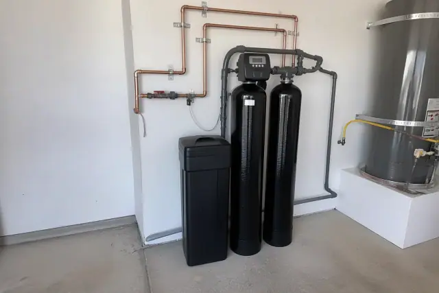 Dual-tank water softener system with copper piping installed in a residential garage in Tempe, AZ.