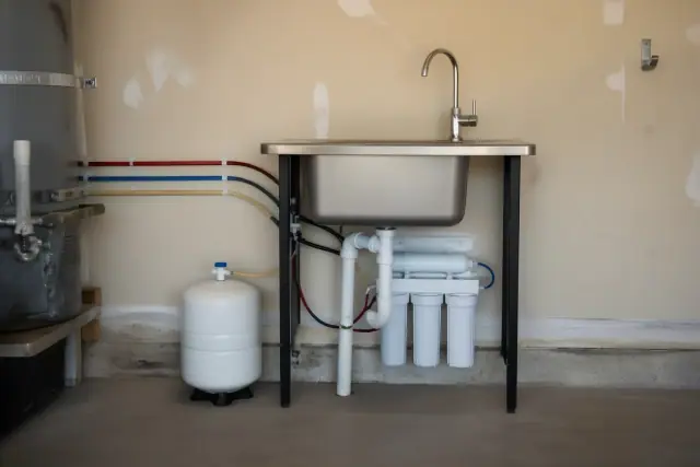 Under sink reverse osmosis water filter installation with a chrome faucet in a residential garage in Tempe, AZ.