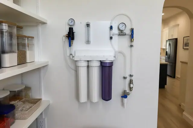 Professional water testing panel with clear tubes and gauges mounted on a pantry wall in a home in Tempe, AZ.