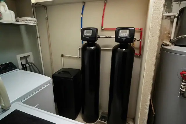Dual-tank water softener system with PEX plumbing installed in a laundry room in Tempe, AZ.