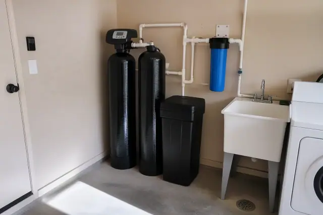 Water softener and filtration system with blue sediment filter in an Avondale, AZ laundry room.