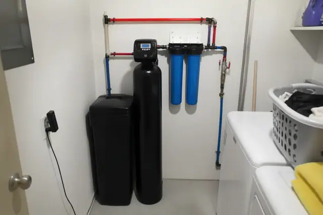 Newly serviced water softener and filtration system with PEX piping in a Tempe, AZ laundry room.