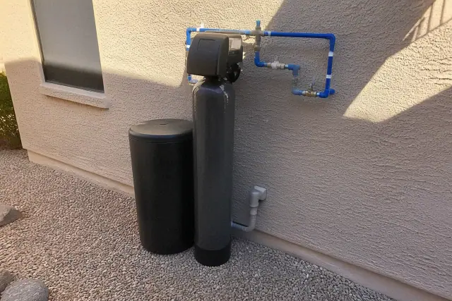 A water softener system with PEX plumbing installed against a stucco wall in Goodyear, AZ.