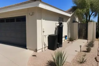 PFAS water filtration system installed on a stucco wall with desert succulents in a Tempe, AZ yard.
