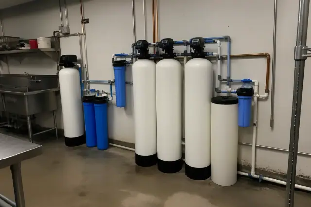 Commercial water filtration system with white and blue tanks installed in a restaurant back room in Surprise, AZ.