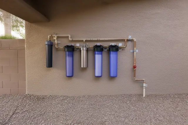 PFAS water filtration system with piping installed on an exterior wall at a home in Gilbert, AZ.