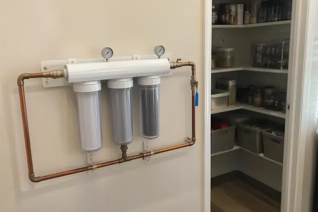 Water filtration system with copper piping and filter housings installed in a residential pantry in Tempe, AZ.