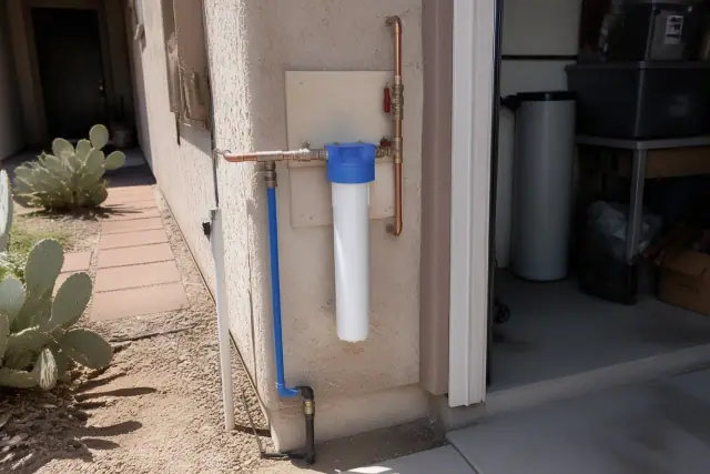 Water filtration unit installation on a residential house in Tempe, AZ with plumbing connections and cactus landscaping.