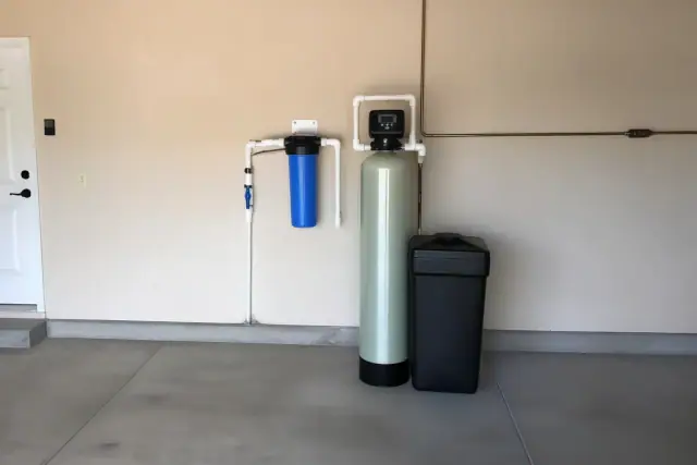 Water softener and filtration system with blue housing and white pipes installed in a Scottsdale, AZ garage.