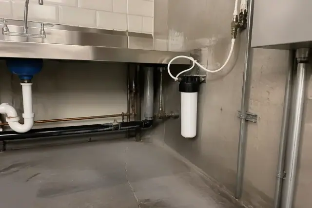 Under-sink water filtration system installed on a concrete wall in a mechanical room in Tempe, AZ.