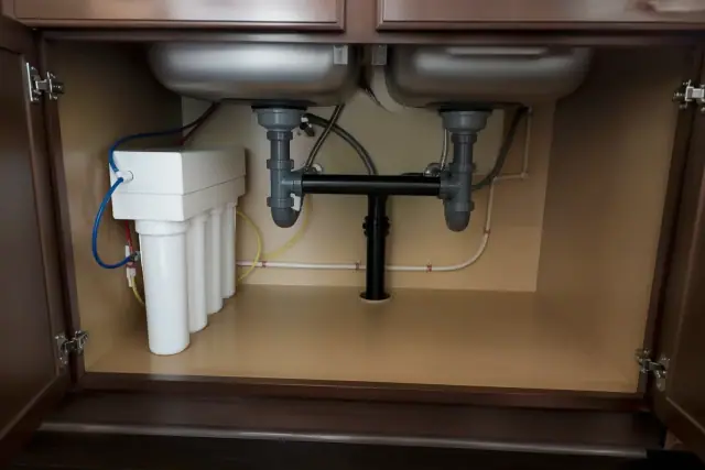 Under-sink water filtration system with clean plumbing installed in a kitchen cabinet in Avondale, AZ.