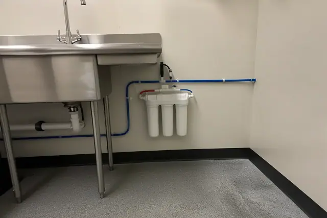Under-sink water filtration system with PEX plumbing installed in a retail utility room in Goodyear, AZ.