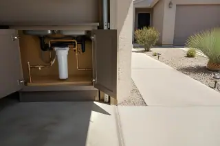 Water filtration housing and copper plumbing connections installed beside a garage in a Tempe, AZ yard.