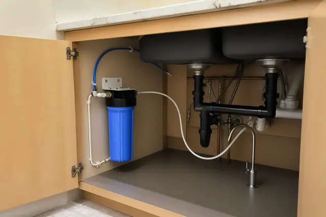 Newly installed under-sink water filtration system with clean PEX tubing in a Mesa, AZ laundry room.