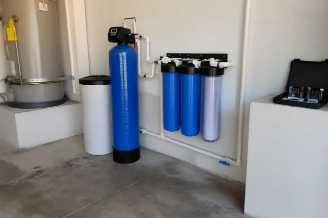 Water softener and filtration system installed next to a water heater in a garage in Mesa, AZ.